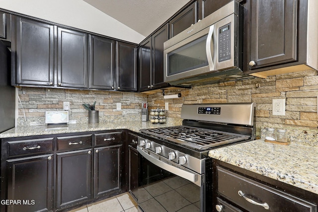 kitchen featuring appliances with stainless steel finishes, decorative backsplash, light stone countertops, and light tile patterned flooring