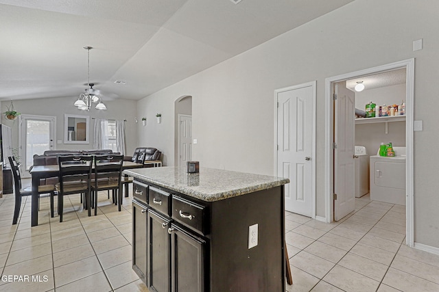 kitchen with arched walkways, light tile patterned floors, a notable chandelier, lofted ceiling, and washer and clothes dryer