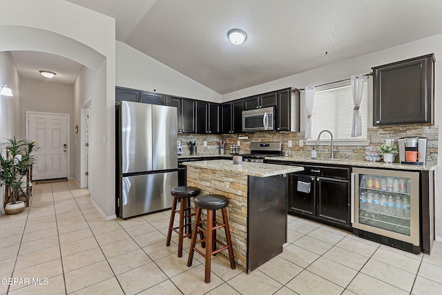 kitchen with beverage cooler, appliances with stainless steel finishes, a sink, and light tile patterned floors