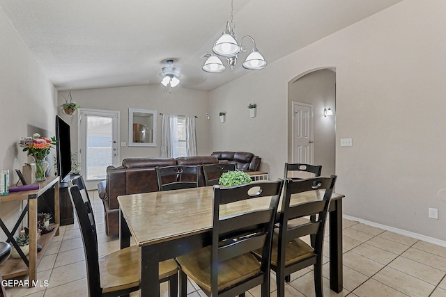 dining space with baseboards, a chandelier, arched walkways, light tile patterned floors, and vaulted ceiling