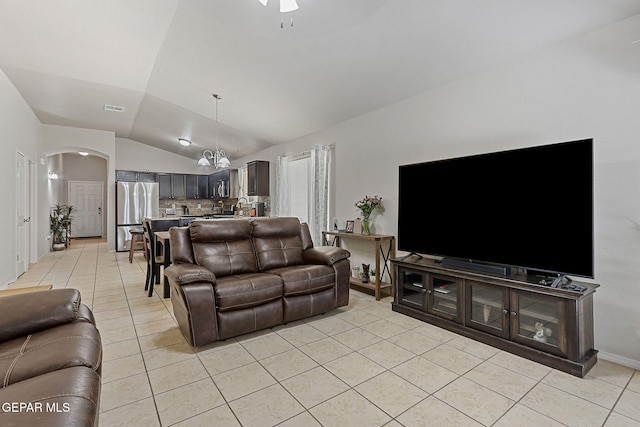 living room featuring ceiling fan, visible vents, arched walkways, vaulted ceiling, and light tile patterned floors