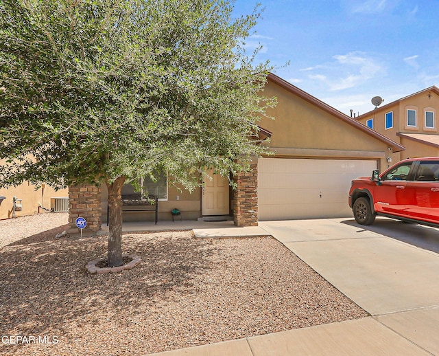 view of front facade featuring central air condition unit, an attached garage, concrete driveway, and stucco siding