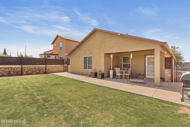 back of property with a yard, a patio, fence, and stucco siding
