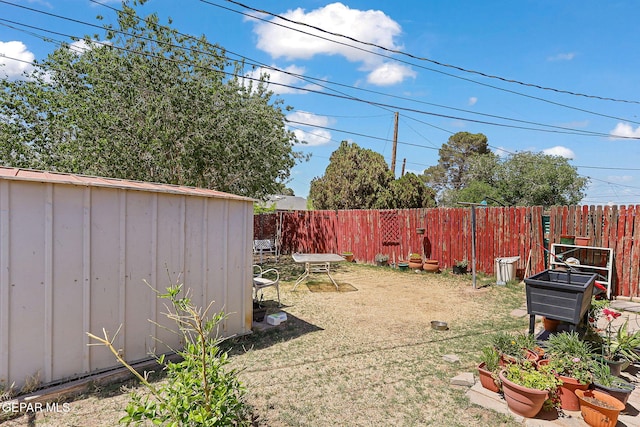 view of yard with a fenced backyard, a storage unit, and an outdoor structure