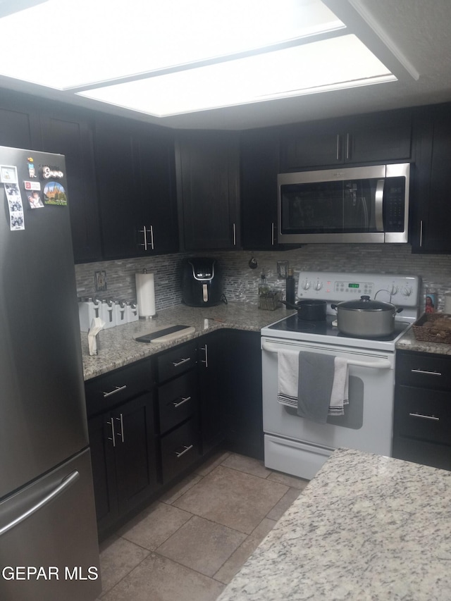 kitchen featuring stainless steel appliances, tasteful backsplash, and dark cabinets