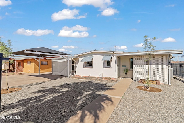view of front of house with stucco siding, fence, and a carport