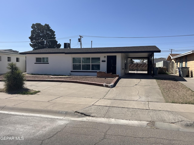 ranch-style home with concrete driveway, an attached carport, and stucco siding