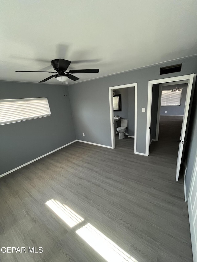 unfurnished bedroom featuring baseboards, a ceiling fan, dark wood-style flooring, and ensuite bath