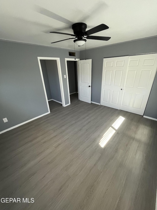 unfurnished bedroom featuring baseboards, ceiling fan, dark wood finished floors, and visible vents