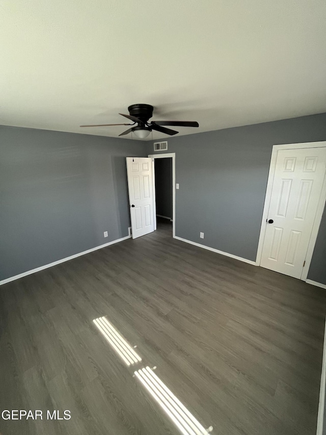 unfurnished bedroom with visible vents, a ceiling fan, baseboards, and dark wood-style flooring