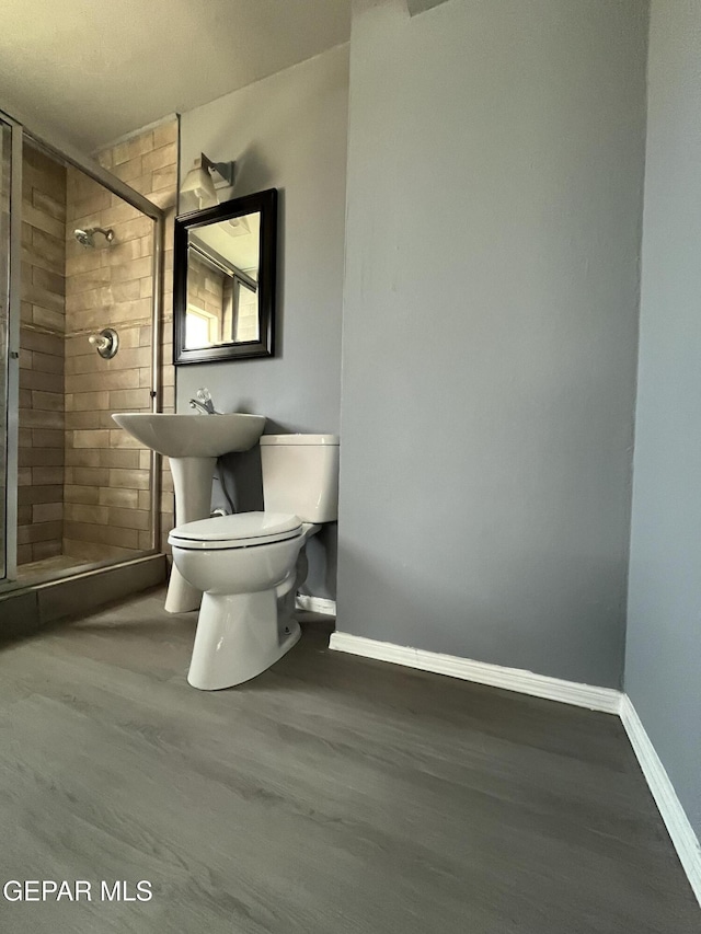 full bath with baseboards, a stall shower, toilet, and wood finished floors