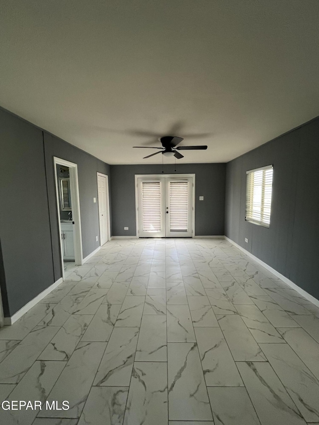 empty room with a ceiling fan, baseboards, and marble finish floor