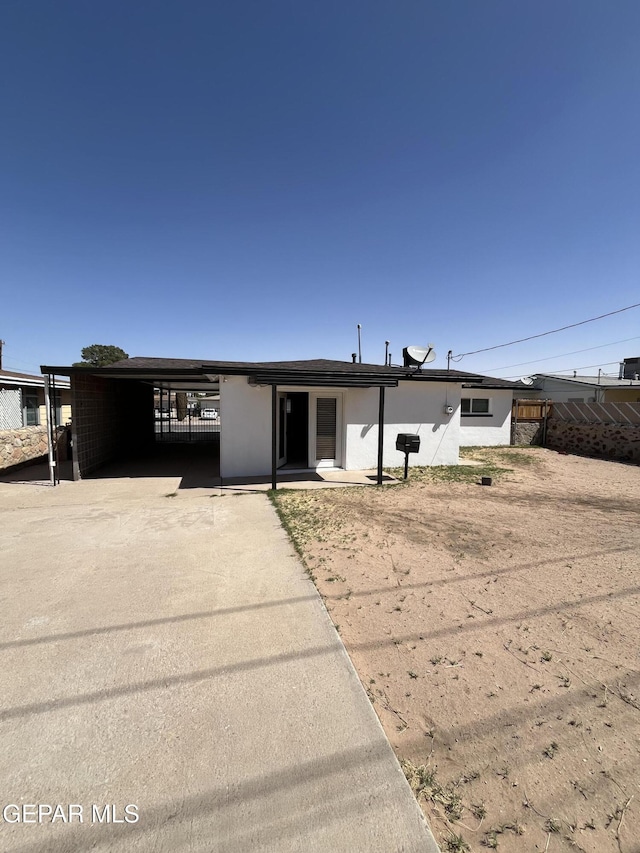 view of front facade featuring stucco siding, driveway, and an attached carport