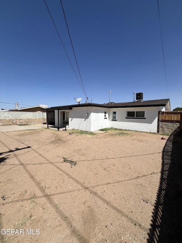 rear view of house featuring fence and stucco siding