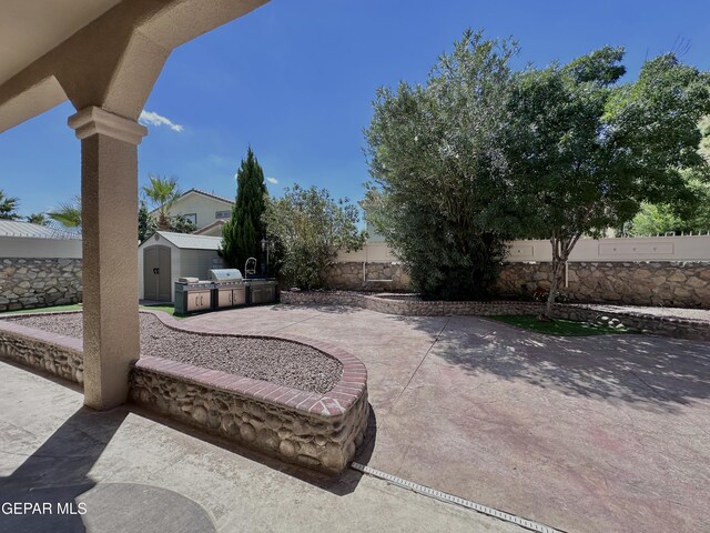 1363 Golden Trail Ln, El Paso, TX 79936 - view of patio / terrace with a shed, a fenced backyard, an outdoor structure, and an outdoor kitchen