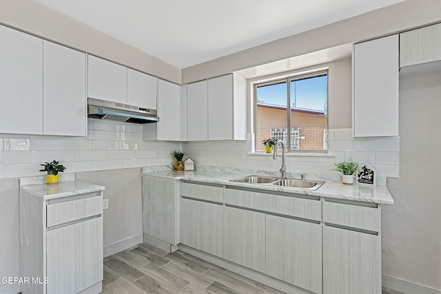 7113 Pear Tree Ln, El Paso, TX 79915 - kitchen featuring under cabinet range hood, a sink, backsplash, light wood-style floors, and baseboards