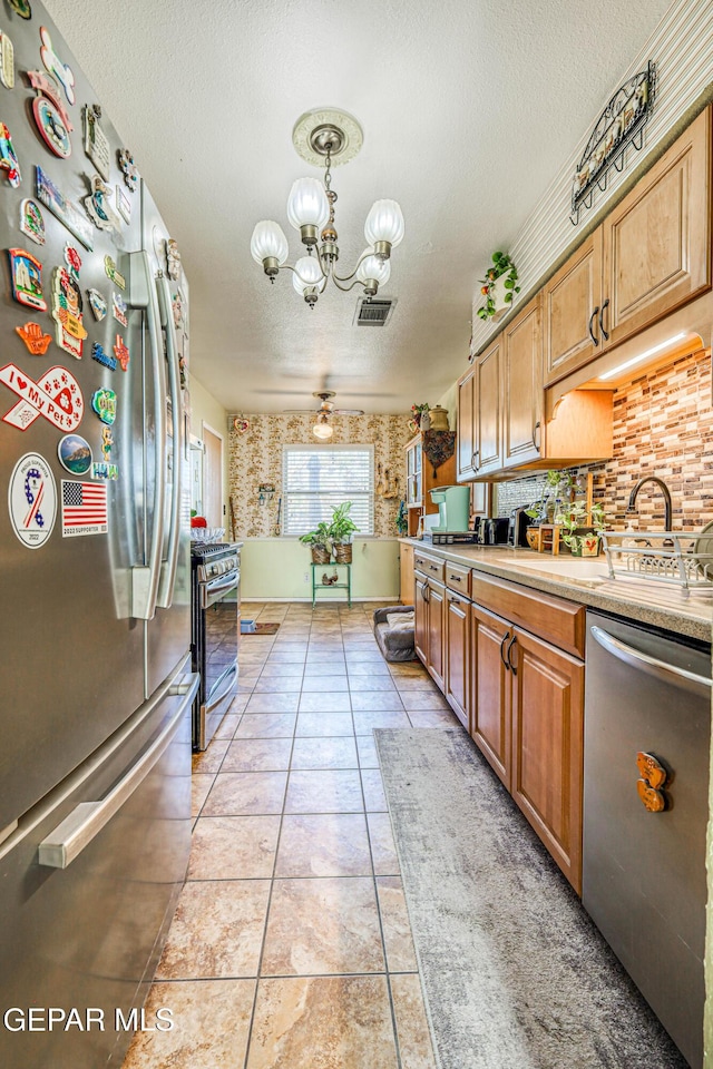 kitchen with an inviting chandelier, light countertops, stainless steel appliances, and a textured ceiling