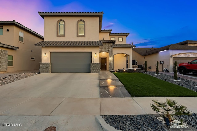 mediterranean / spanish home with a tiled roof, a garage, a front lawn, concrete driveway, and stucco siding