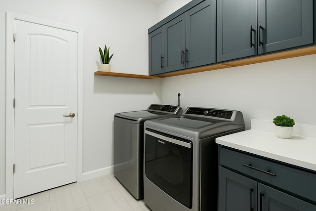 clothes washing area with baseboards, light tile patterned flooring, cabinet space, and washer and dryer