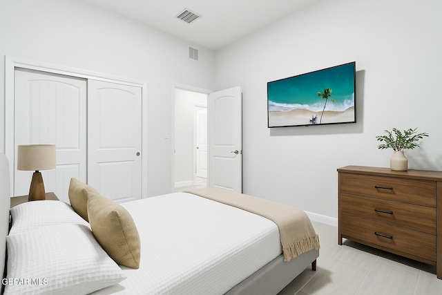 bedroom with light tile patterned floors, baseboards, a closet, and visible vents
