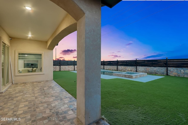 yard at dusk with a fenced backyard, a pool with connected hot tub, and a patio area