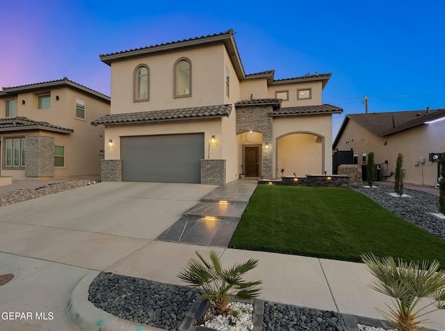 mediterranean / spanish house featuring an attached garage, stucco siding, a front yard, concrete driveway, and a tiled roof
