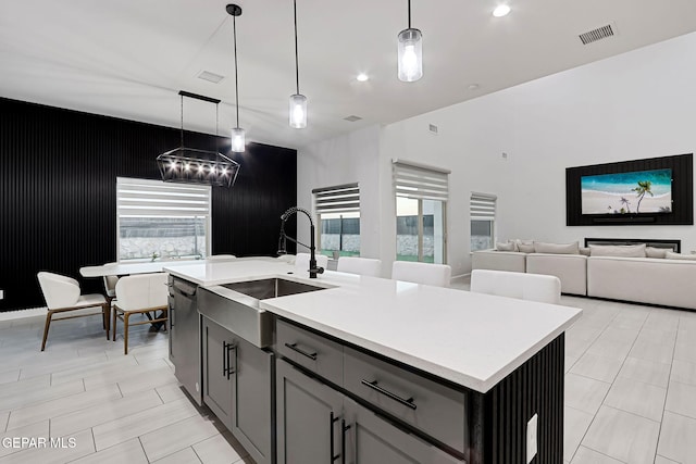 kitchen featuring decorative light fixtures, visible vents, dishwasher, a sink, and light countertops