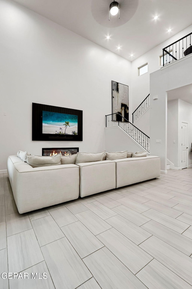 living room with stairway, baseboards, ceiling fan, and recessed lighting