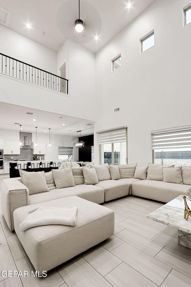 living room featuring visible vents, a high ceiling, and a healthy amount of sunlight
