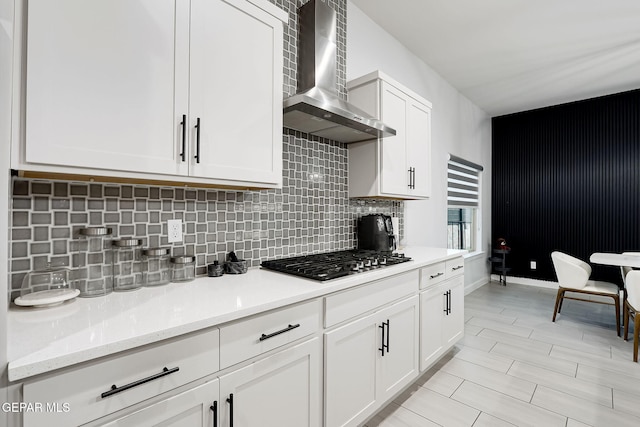 kitchen featuring white cabinets, tasteful backsplash, wall chimney range hood, and stainless steel gas stovetop
