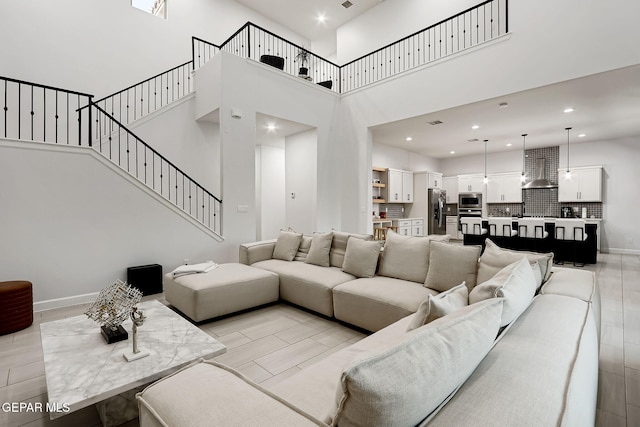 living area featuring recessed lighting, baseboards, stairway, and a towering ceiling