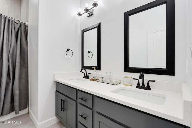 full bath with double vanity, baseboards, curtained shower, and a sink