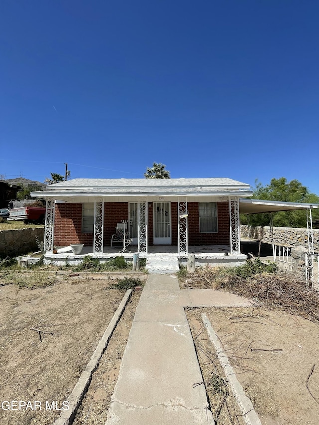 view of front of home featuring covered porch, a carport, and brick siding