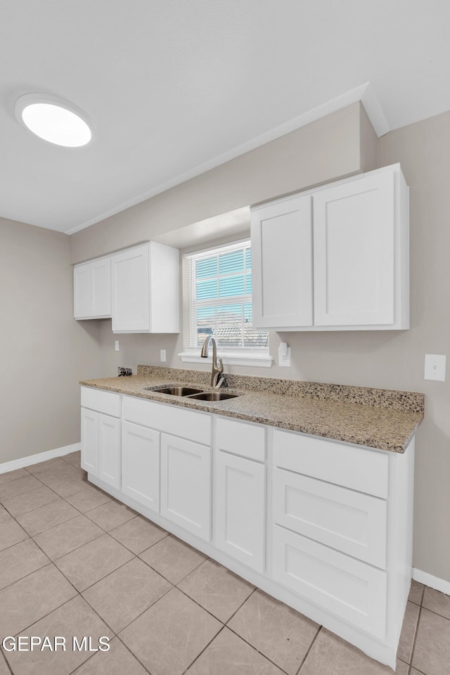 10601 Teresa Pl, El Paso, TX 79924 - kitchen with a sink, light tile patterned flooring, baseboards, white cabinets, and light stone countertops