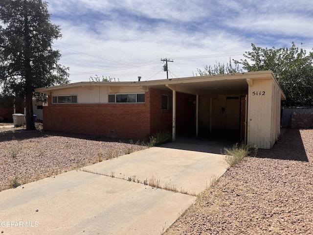 ranch-style home featuring concrete driveway, brick siding, and a carport