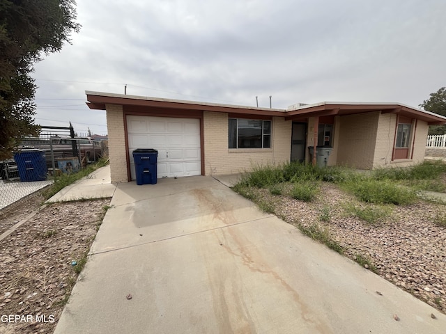 ranch-style house with a garage, fence, concrete driveway, and brick siding