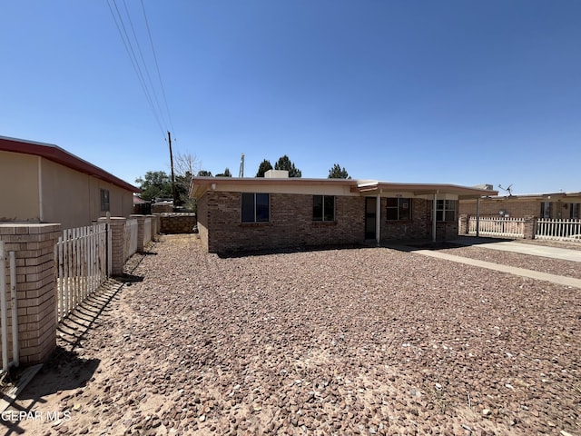 rear view of house featuring fence and brick siding