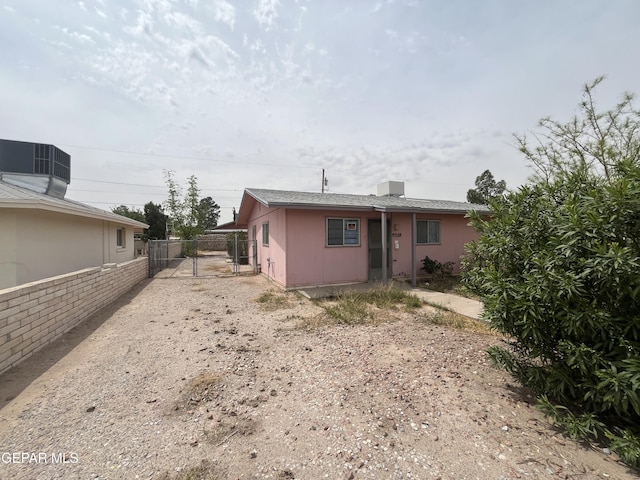 rear view of house featuring central AC unit, fence, and a gate