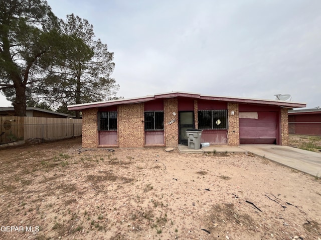 mid-century home with brick siding, fence, driveway, and a garage