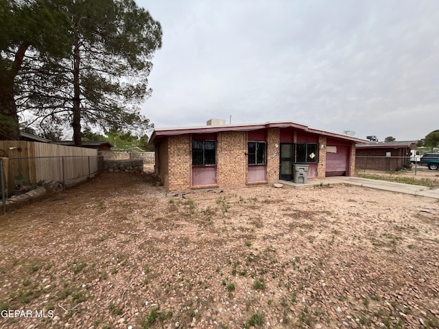 rear view of property featuring brick siding, fence, and a garage