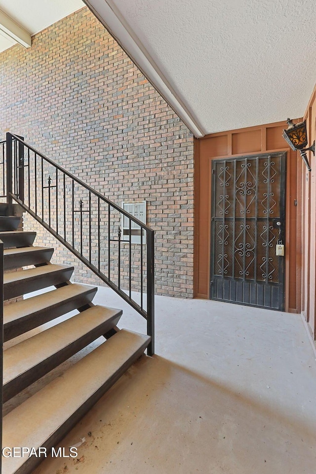 4800 N Stanton St Unit 87, El Paso, TX 79902 - stairway with brick wall, lofted ceiling, and a textured ceiling