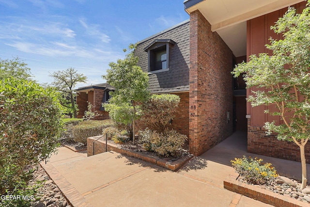 4800 N Stanton St Unit 87, El Paso, TX 79902 - view of property exterior featuring a patio area, roof with shingles, and brick siding
