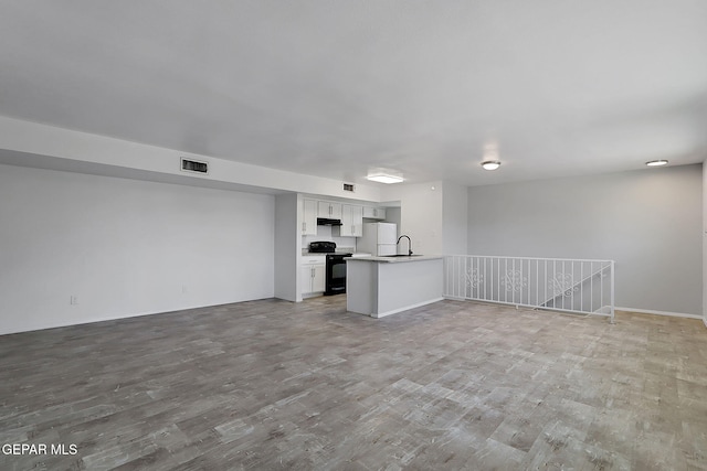 unfurnished living room with visible vents, a sink, and wood finished floors