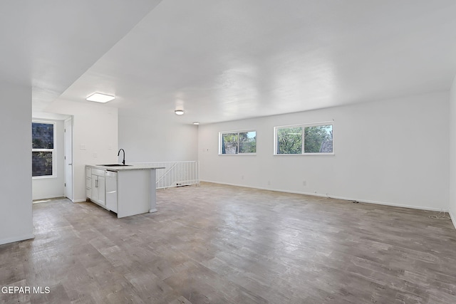 unfurnished living room with baseboards, a sink, and light wood finished floors