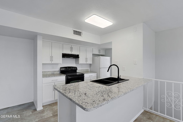 kitchen featuring visible vents, freestanding refrigerator, black electric range oven, under cabinet range hood, and a sink