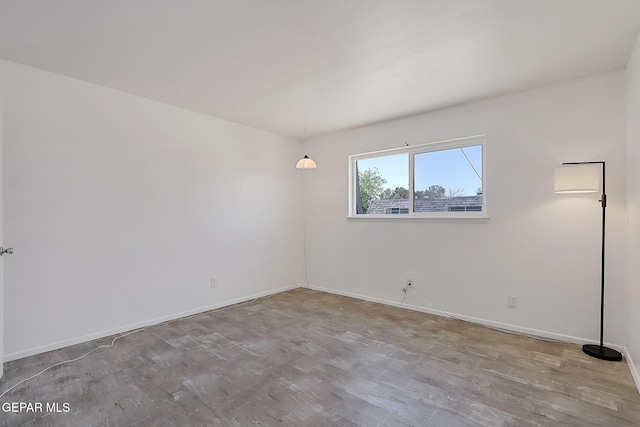 spare room with baseboards and wood finished floors