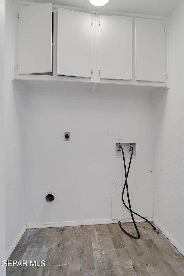 clothes washing area featuring washer hookup, baseboards, cabinet space, and wood finished floors