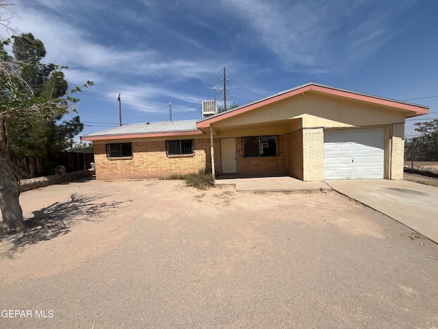 ranch-style house featuring fence, brick siding, a garage, covered porch, and driveway