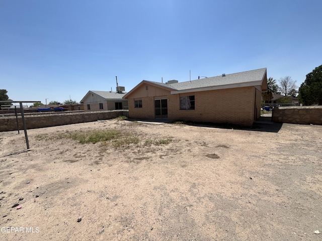 rear view of house with brick siding and fence