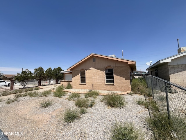 view of side of property with brick siding and fence